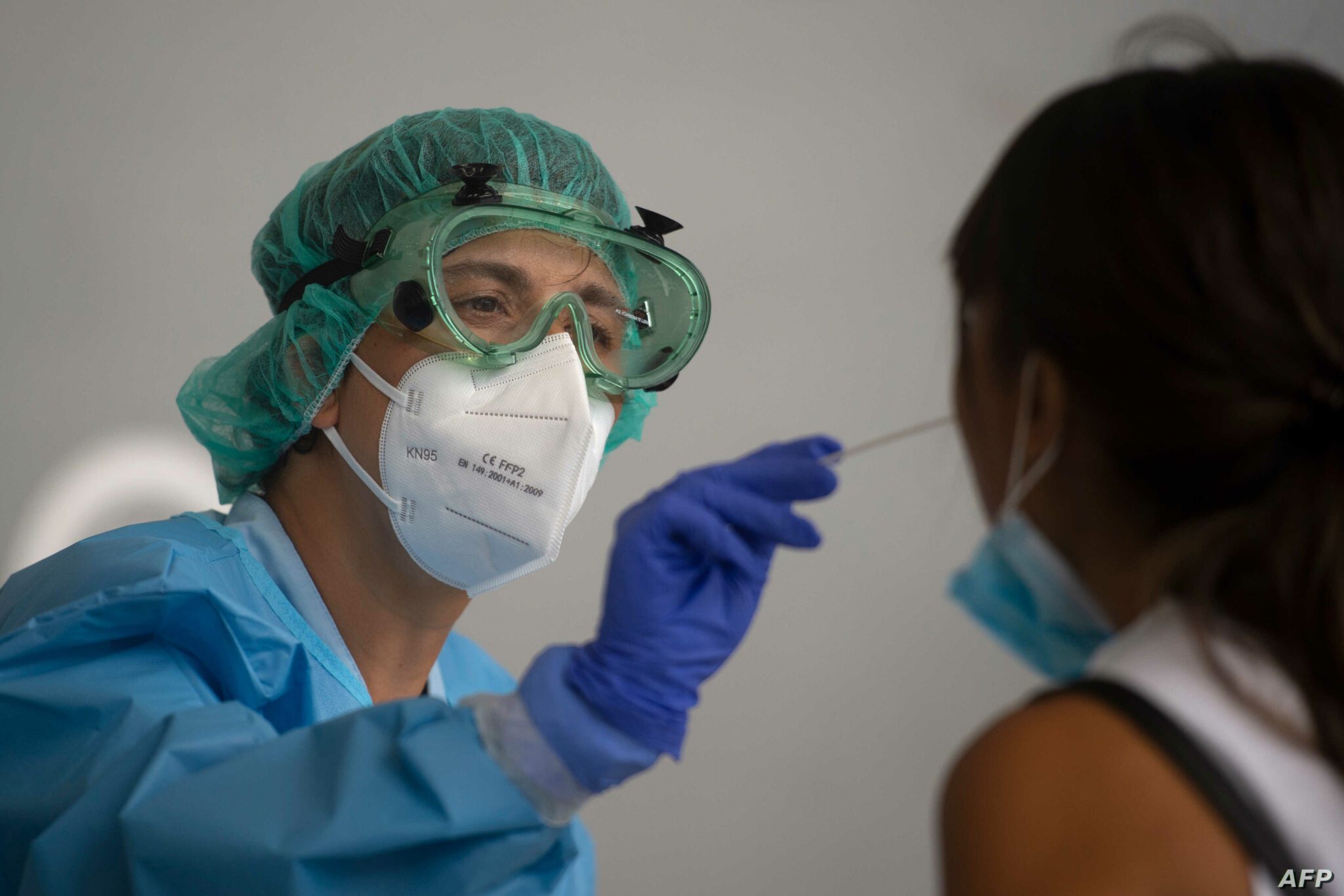 SPAIN-HEALTH-VIRUS A healthcare worker uses a swab to collect a sample from a woman at a temporary testing centre for the novel coronavirus in Spanish Basque city of Azpeitia on August 15, 2020 following a new outbreak in the city. - Spain said it was closing discos and banning smoking in the street without social distancing, as it stepped up restrictions to stop the spread of the new coronavirus. (Photo by ANDER GILLENEA / AFP)