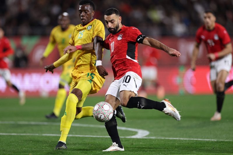 Zimbabwe's defender #15 Teenage Hadebe challenges Egypt's forward #10 Mohamed Salah during the Africa Cup of Nations (CAN) group B football match between Egypt and Zimbabwe at Adrar Stadium in Agadir on December 22, 2025. (Photo by FRANCK FIFE / AFP)